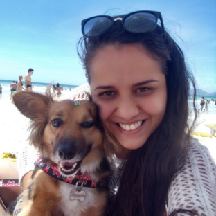 Mulher e cachorro abraçados com o mar e céu azul ao fundo 